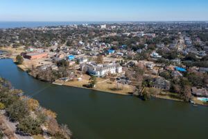 Aerial view of a cityscape featuring a river and residential buildings surrounded by trees.