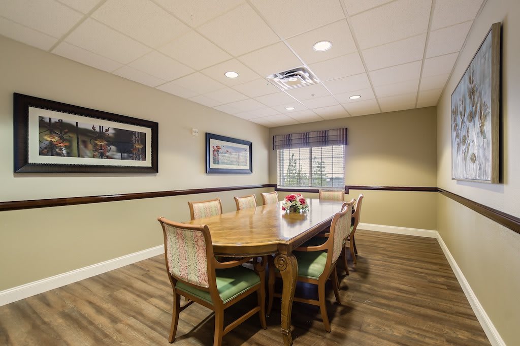 A well-lit conference room with a long wooden table, surrounding chairs, and artwork on the walls.