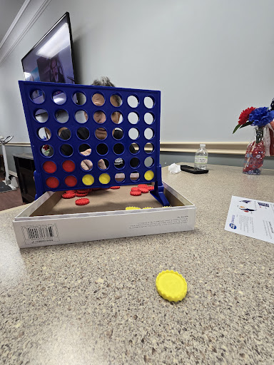 A mid-game view of Connect Four with red and yellow tokens on a table.