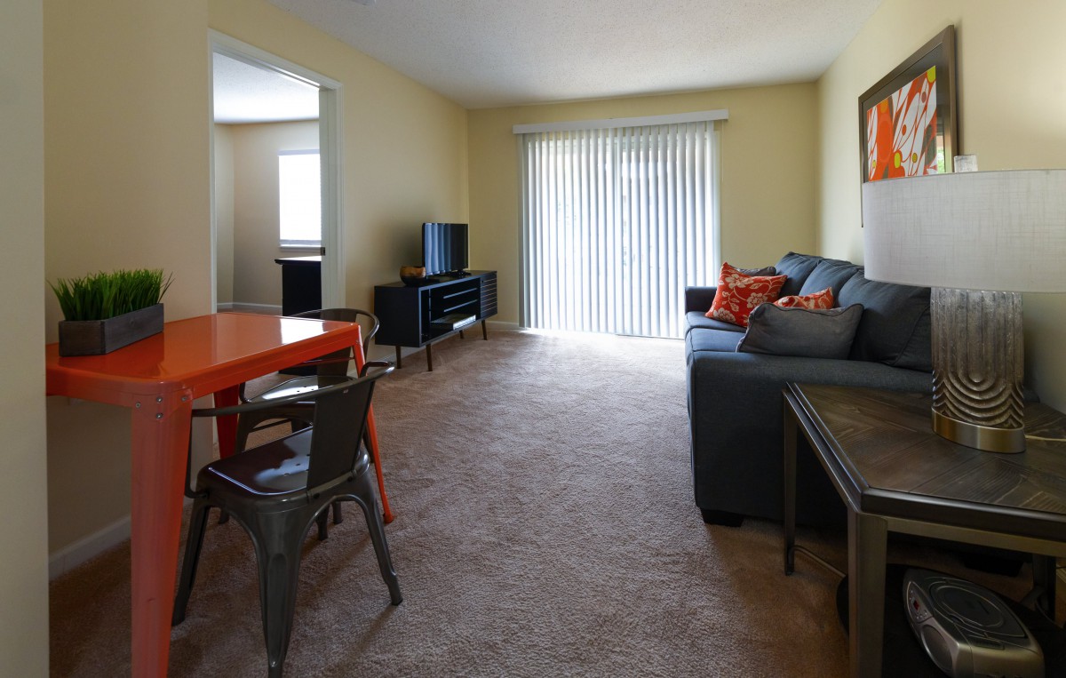 A cozy living room with a sofa, television, and dining area.