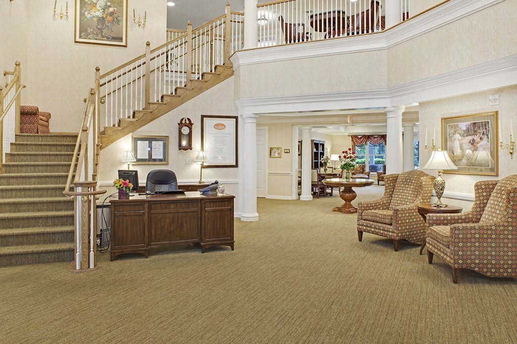 A spacious lobby area featuring a reception desk, comfortable seating, and an elegant staircase.