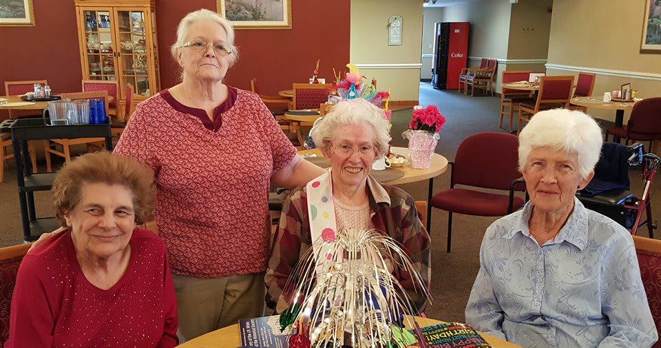 Elderly women celebrating a birthday with cake and decorations.