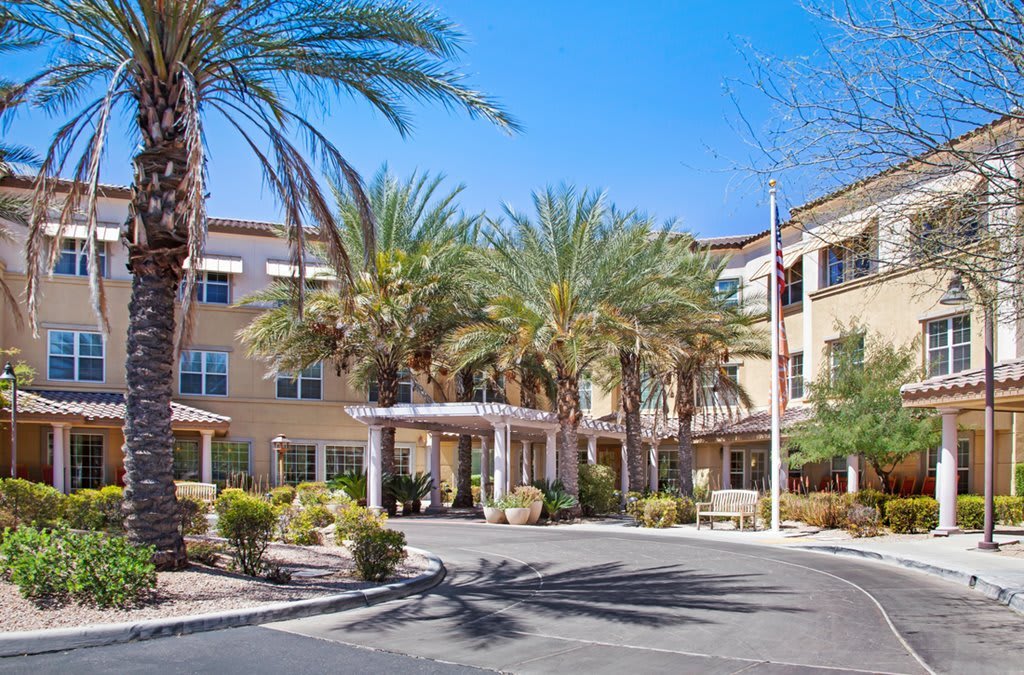 A residential building with a landscaped entrance and palm trees.