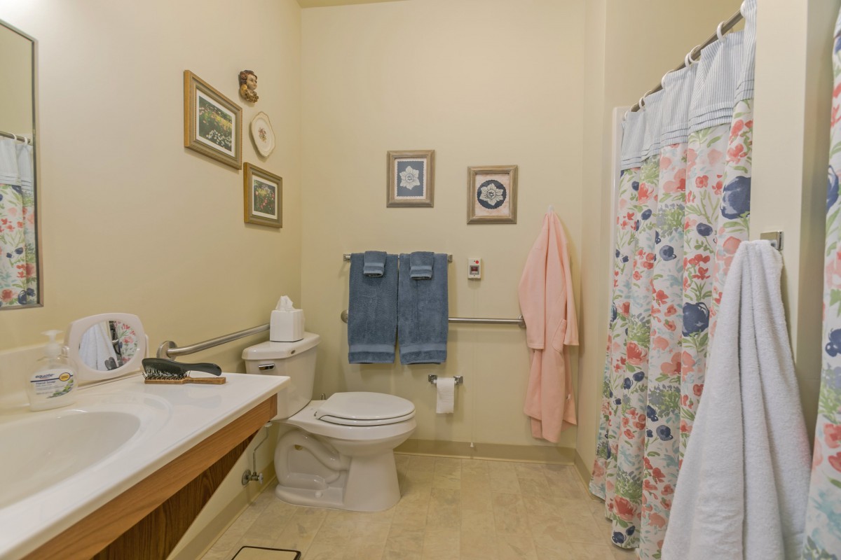 A cozy bathroom with framed art, a floral shower curtain, and neatly hung towels.