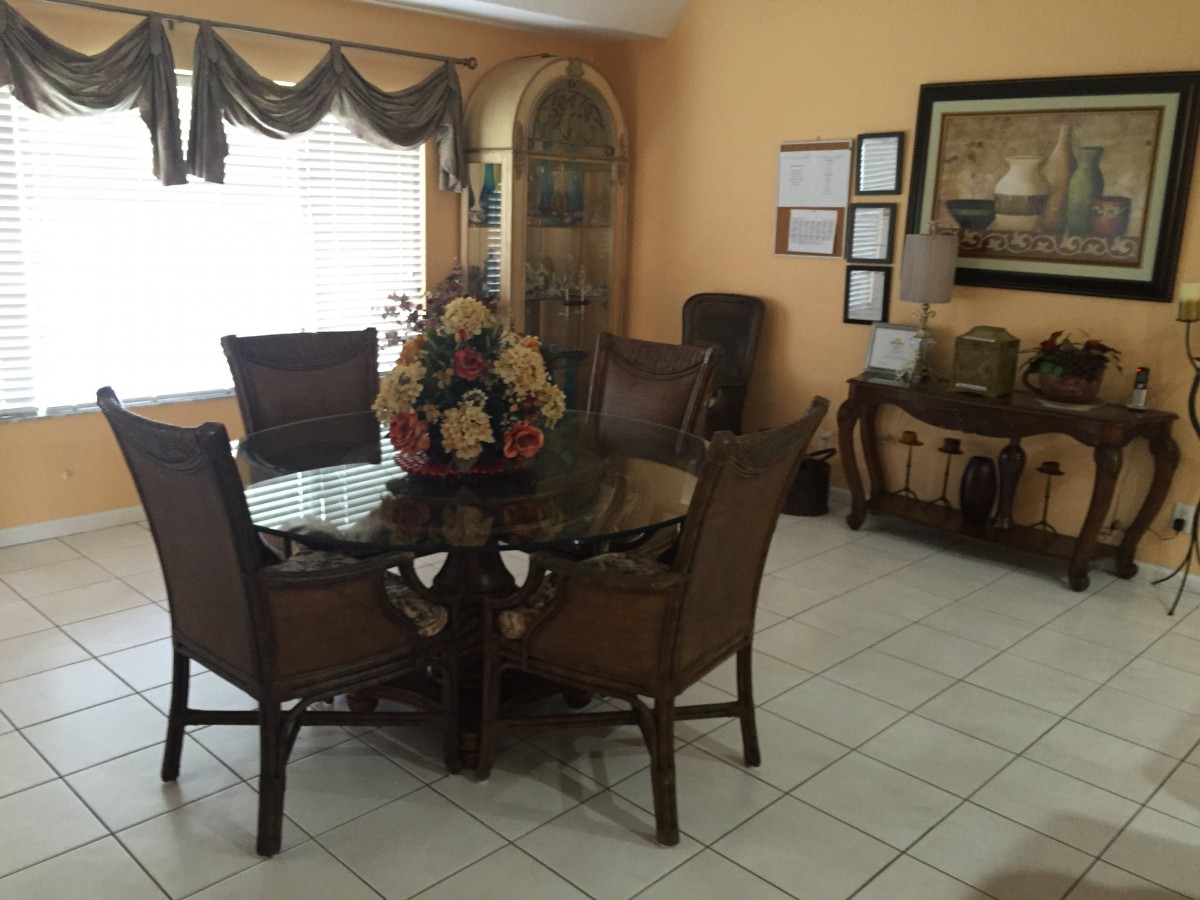 A well-decorated dining room featuring a round table with chairs and a floral centerpiece.