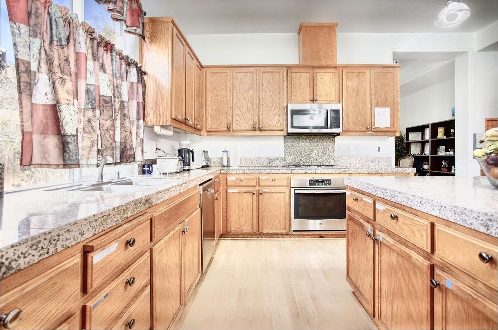 A spacious kitchen featuring wood cabinets, granite countertops, and stainless steel appliances.