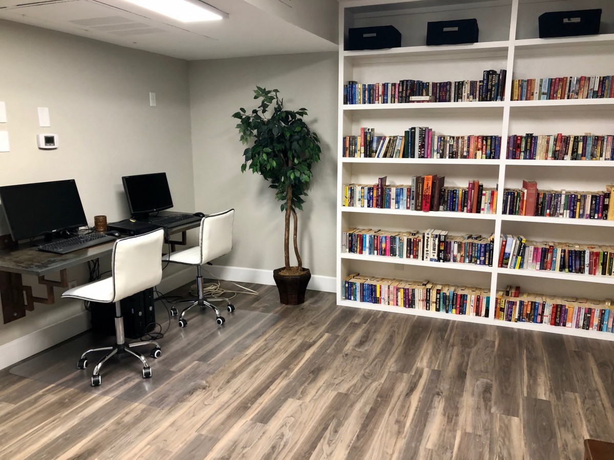 A modern office space with computers and a bookshelf filled with books.