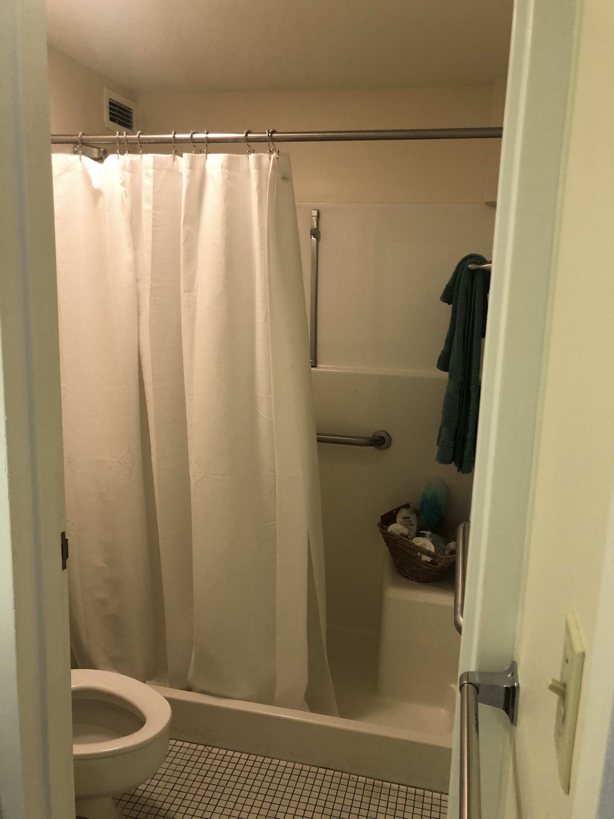 A small bathroom with a shower curtain and towel hanging.