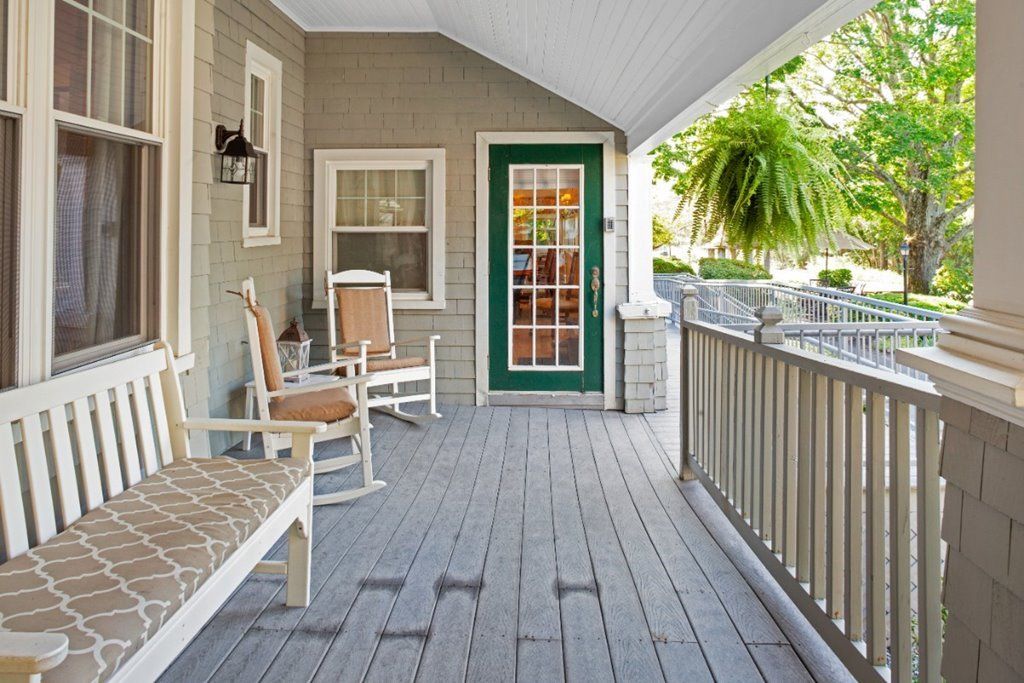 A cozy porch with rocking chairs and a green-bordered front door.