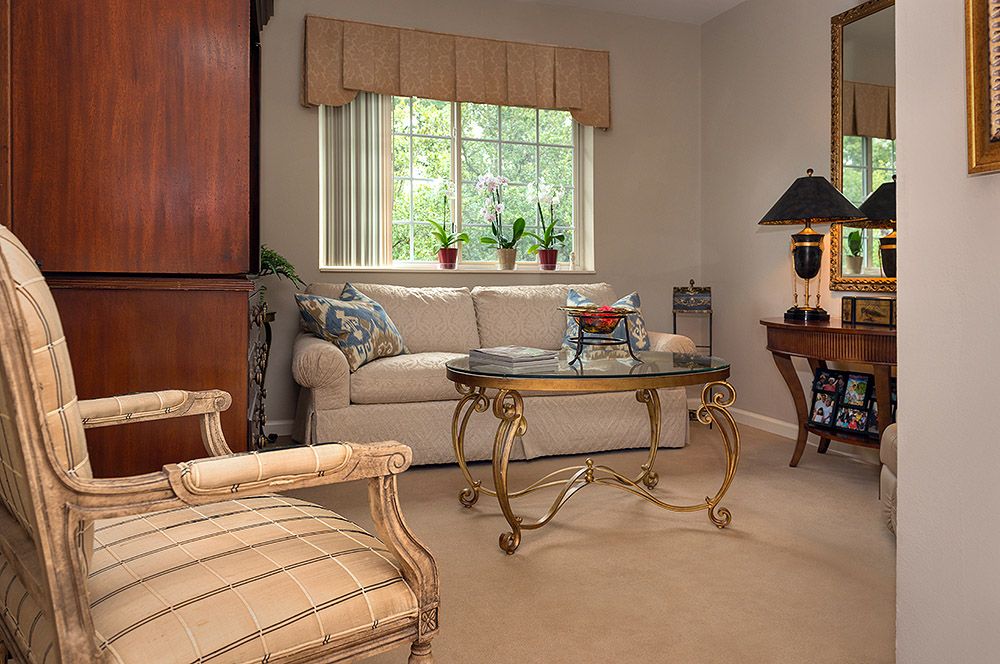 A cozy living room with a sofa, elegant coffee table, and large window with plants.
