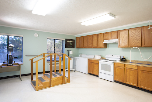 A spacious kitchen featuring wooden cabinets, essential appliances, and a wheelchair-accessible ramp.