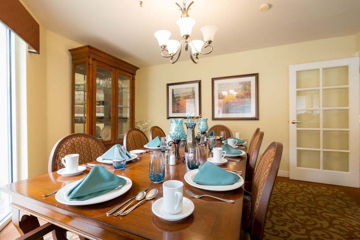 A well-arranged dining room with a wooden table set for a meal, featuring elegant decor and ambient lighting.