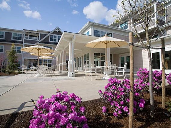A welcoming patio area with umbrellas and blooming flowers outside a building.