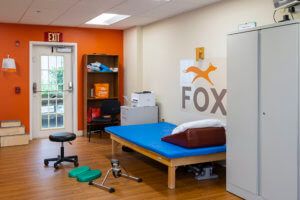 A physical therapy clinic room with a therapy bed and exercise equipment.