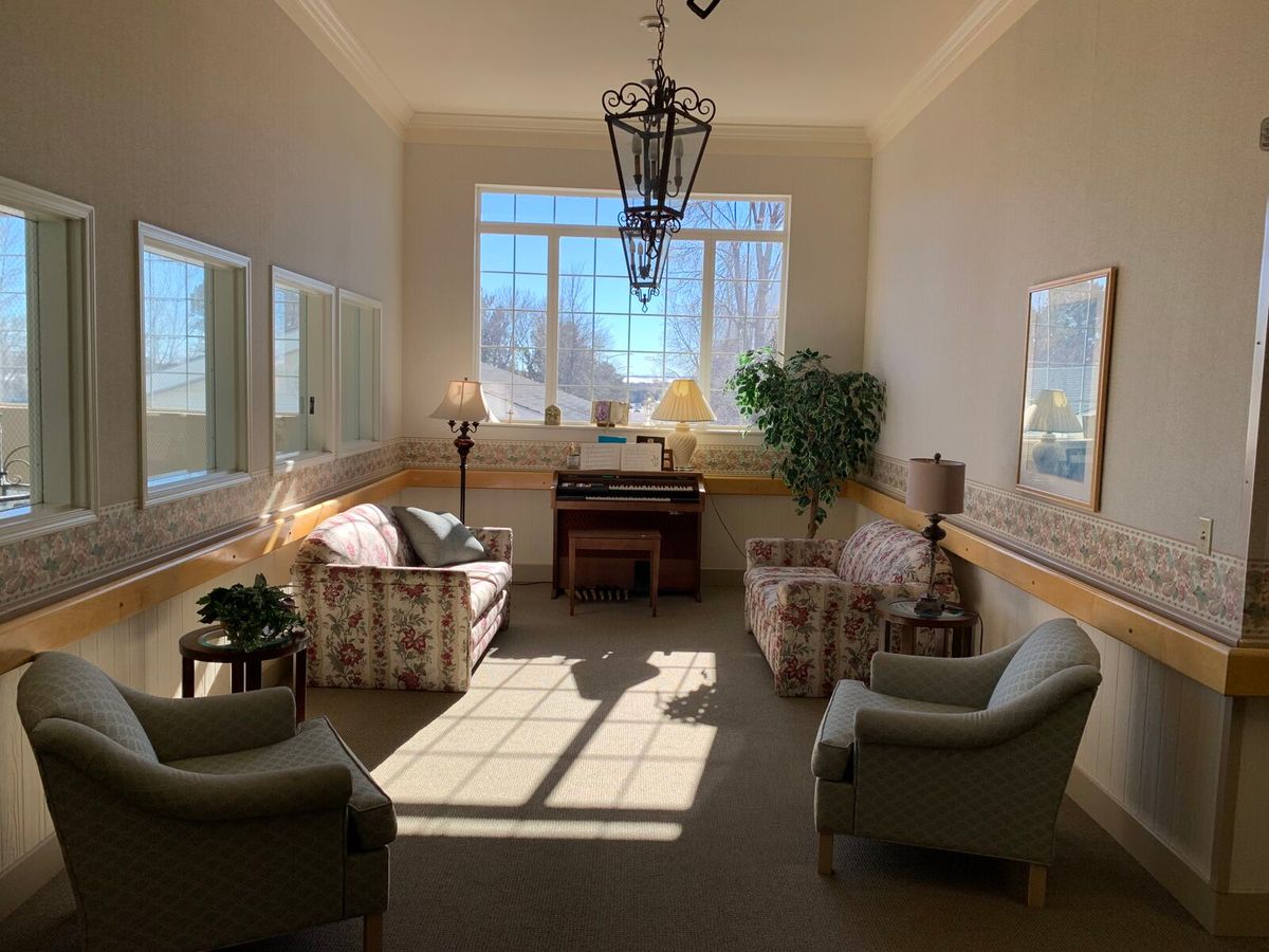 A cozy sunlit seating area with comfortable chairs and a piano.