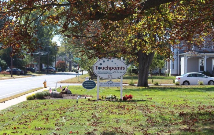 A sign surrounded by trees and grass on a sunny autumn day.