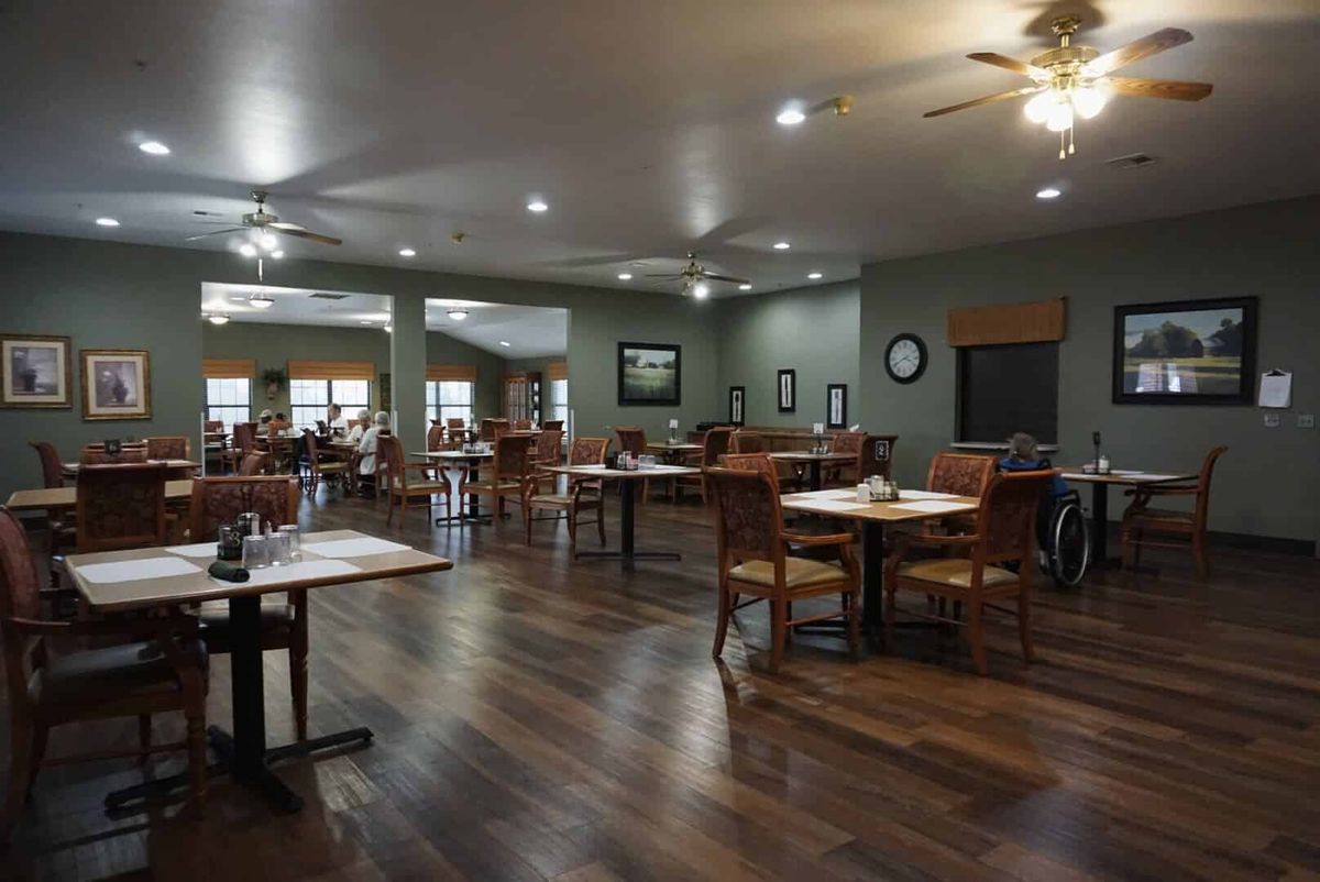 A spacious restaurant dining area with wooden floors and neatly arranged tables and chairs.