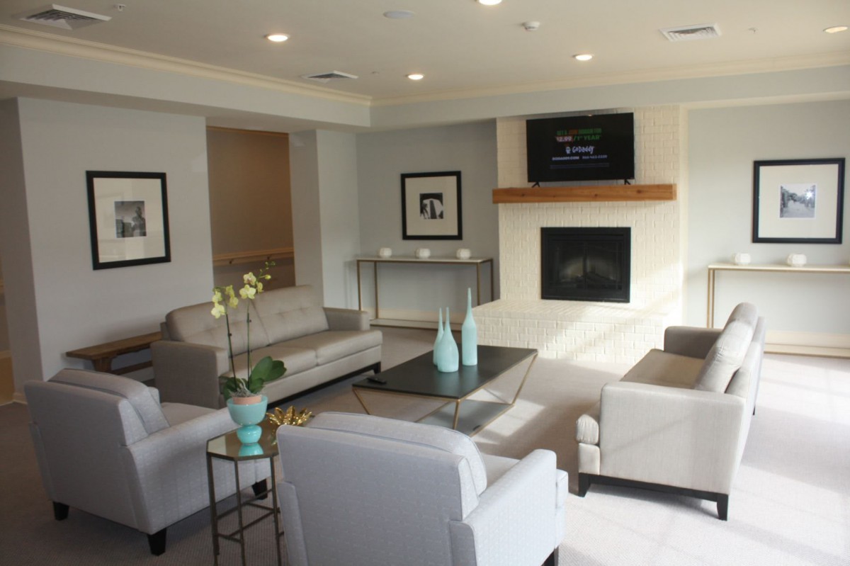 A modern living room with comfortable seating, a TV above a fireplace, and stylish decor.