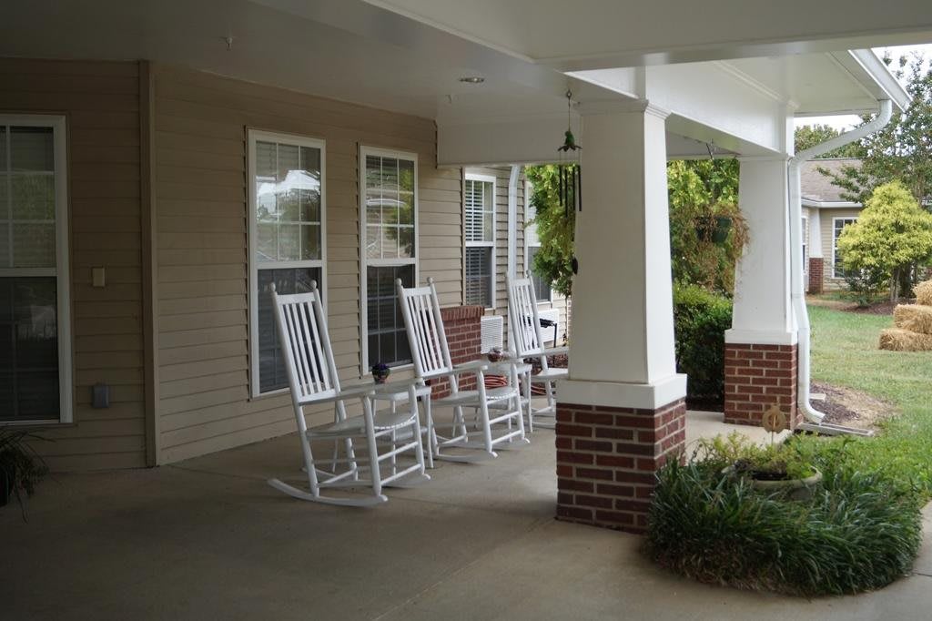 A cozy front porch with white rocking chairs and brick accents.