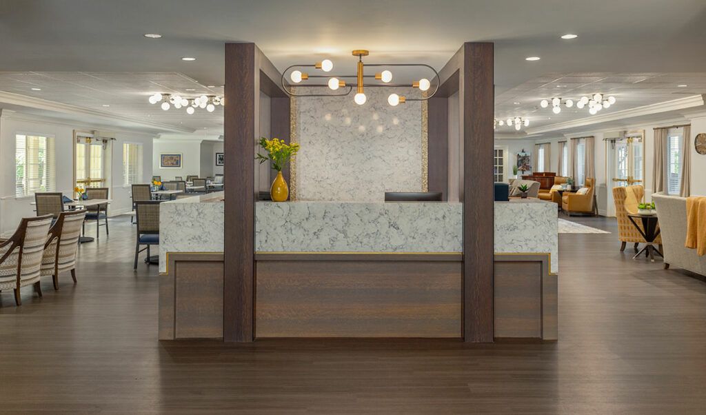 A modern lobby reception area featuring a marble wall, wood flooring, and contemporary lighting.
