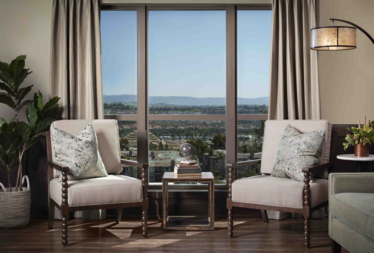 A cozy sitting area with two chairs and a small table overlooking a scenic landscape through a large window.