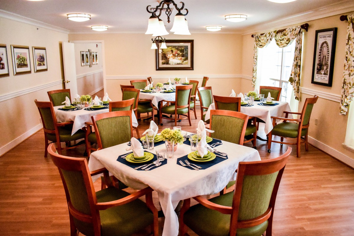 A well-decorated dining room with neatly arranged tables and chairs, featuring elegant table settings.