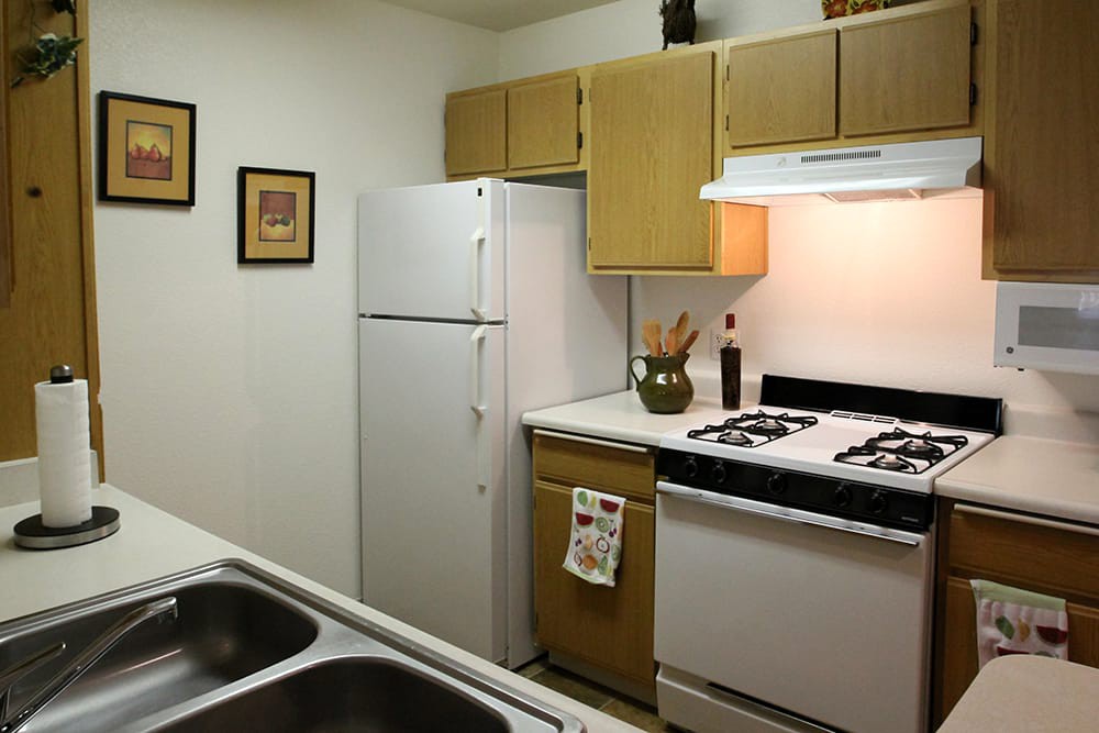 A small kitchen with white appliances and wooden cabinets.