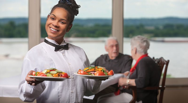 A waitress serves food to customers in a restaurant.