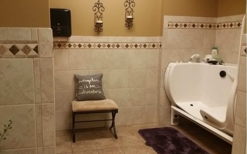 A tastefully decorated bathroom with a cushioned bench and wall art.
