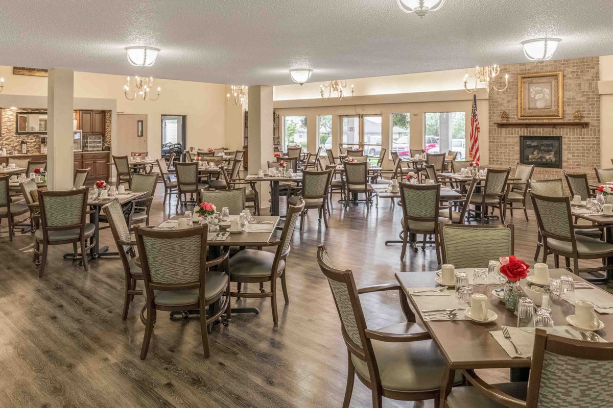 Spacious dining area with neatly arranged tables and chairs, featuring elegant decor and warm lighting.