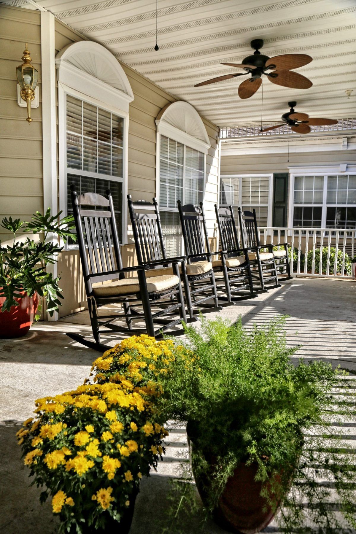 A serene porch setting with rocking chairs and vibrant plants.