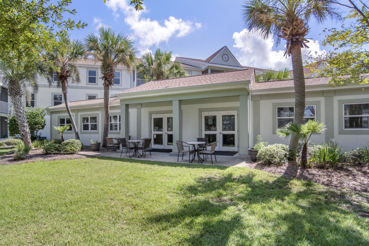 A beautiful house with palm trees and a spacious backyard patio on a sunny day.