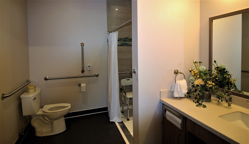 A clean and modern bathroom featuring a toilet, shower, and sink with accessibility features.
