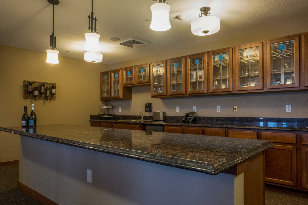 A modern kitchen featuring granite countertops, wooden cabinets, and stylish lighting fixtures.
