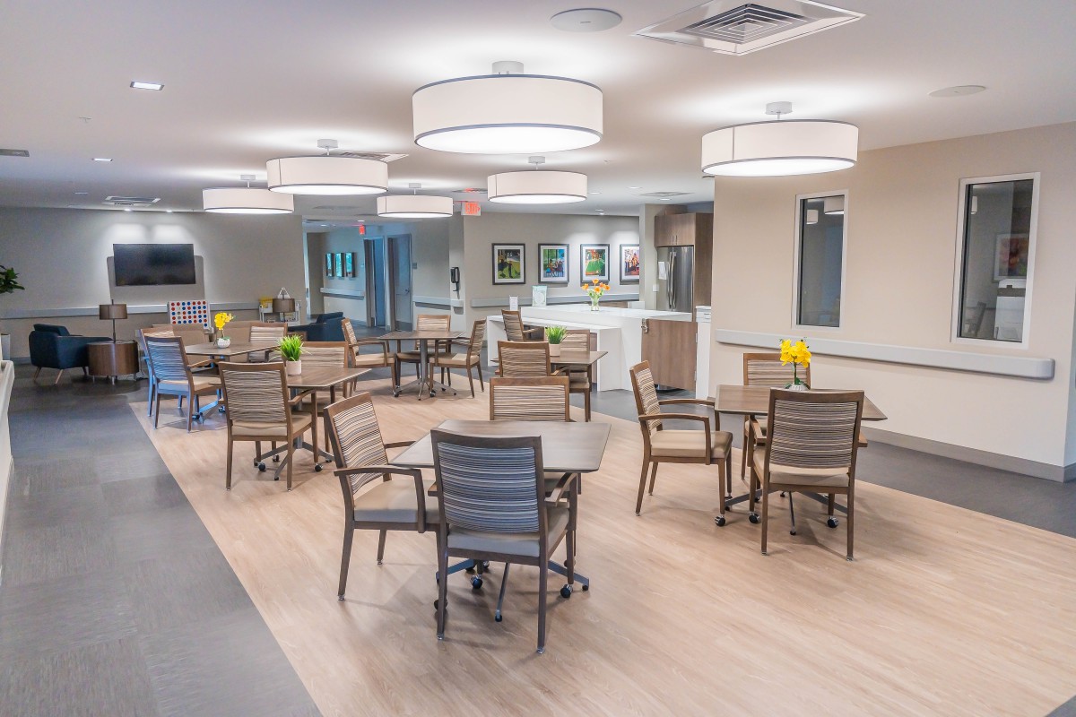 A modern dining area with several tables and chairs, featuring stylish lighting and a clean interior design.