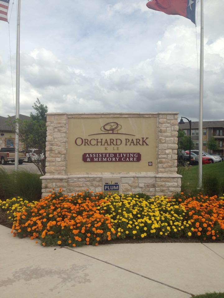 Entrance sign for Orchard Park surrounded by vibrant flowers.