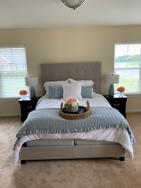 A modern bedroom with a neatly made bed, decorative pillows, and bedside lamps.