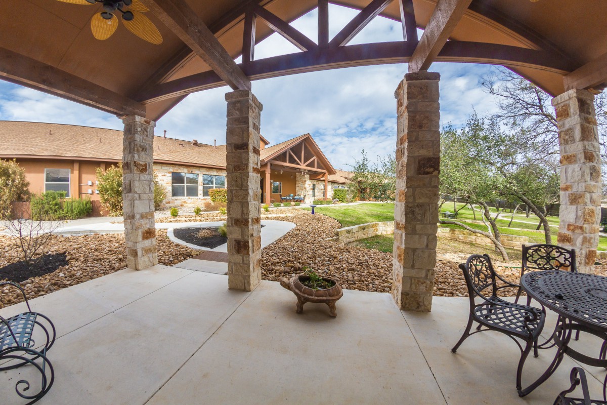 A spacious patio with stone pillars overlooks a landscaped garden.