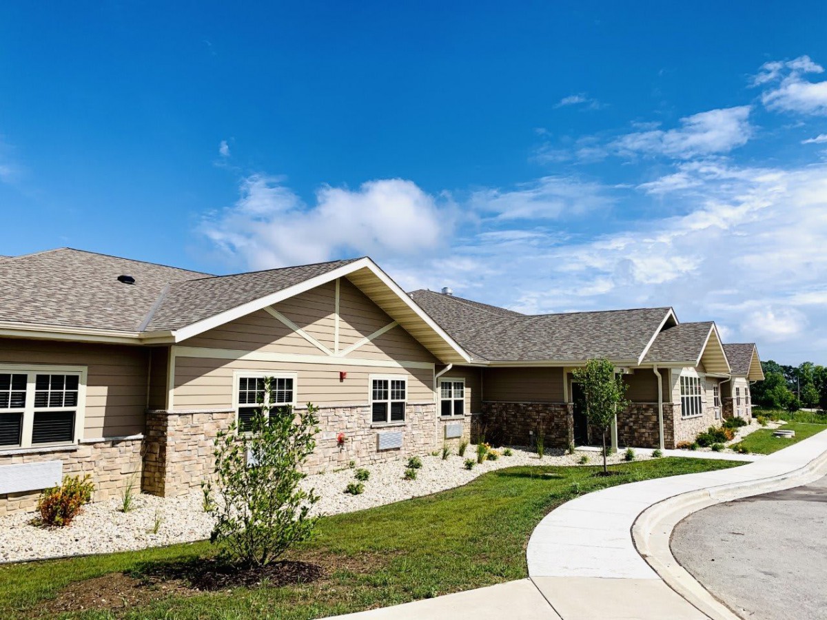 A suburban residential house with well-maintained landscaping under a clear blue sky.