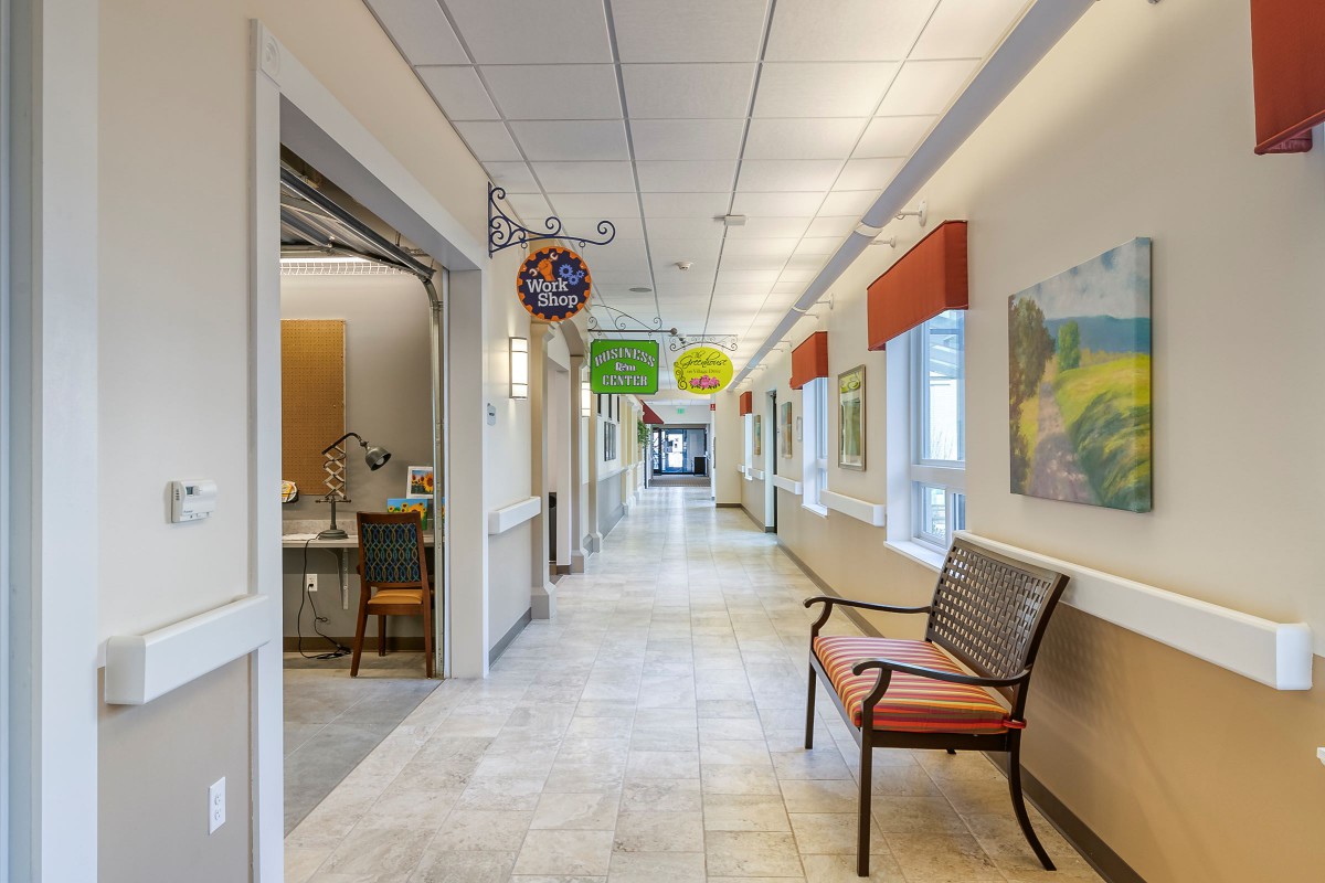 A well-lit hallway in an office setting with benches and directional signs.