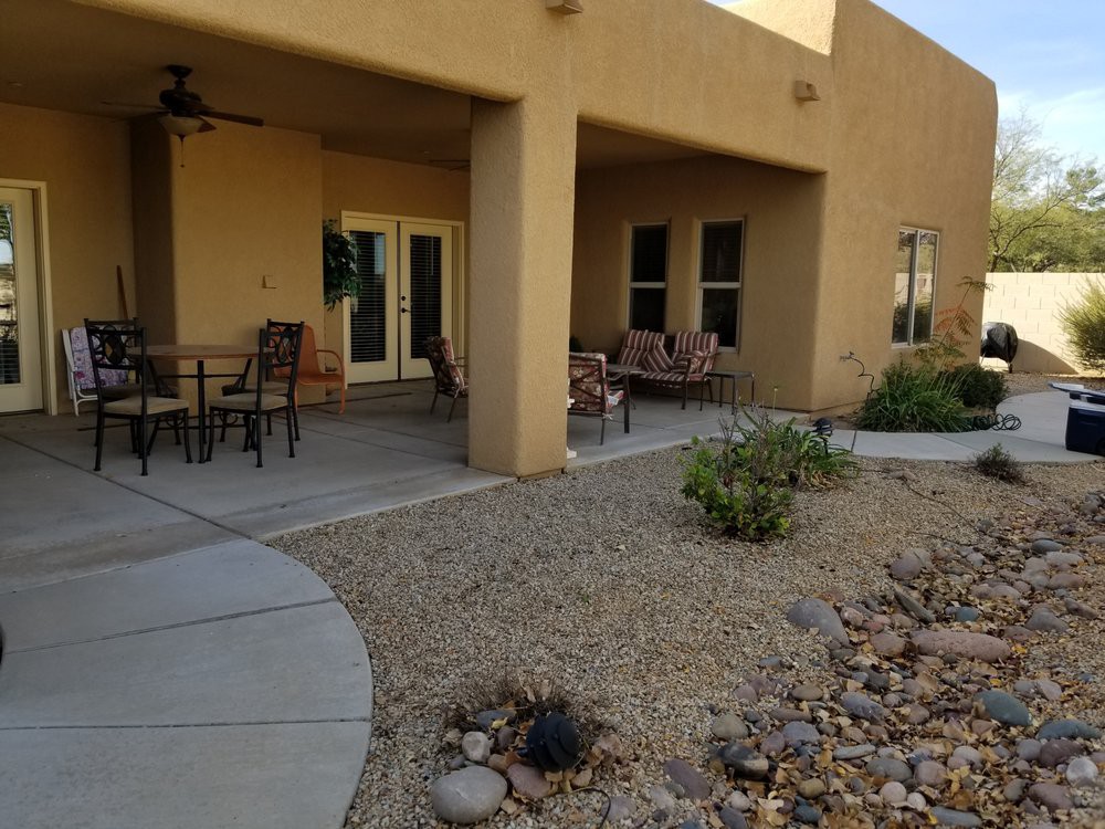 A covered patio area with outdoor seating and desert-style landscaping.