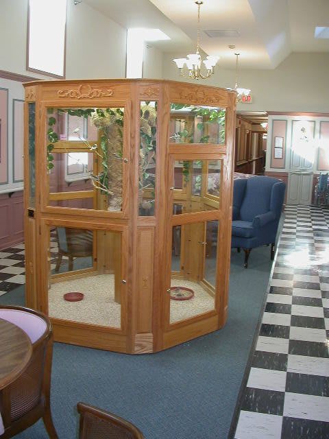 A vintage wooden phone booth situated in an interior space with checkered flooring.