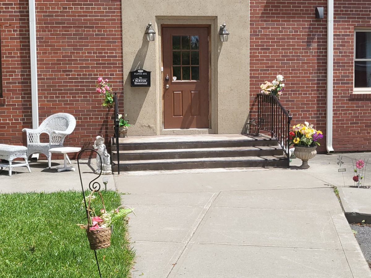 A brick building entrance with stairs and decorative flower pots.