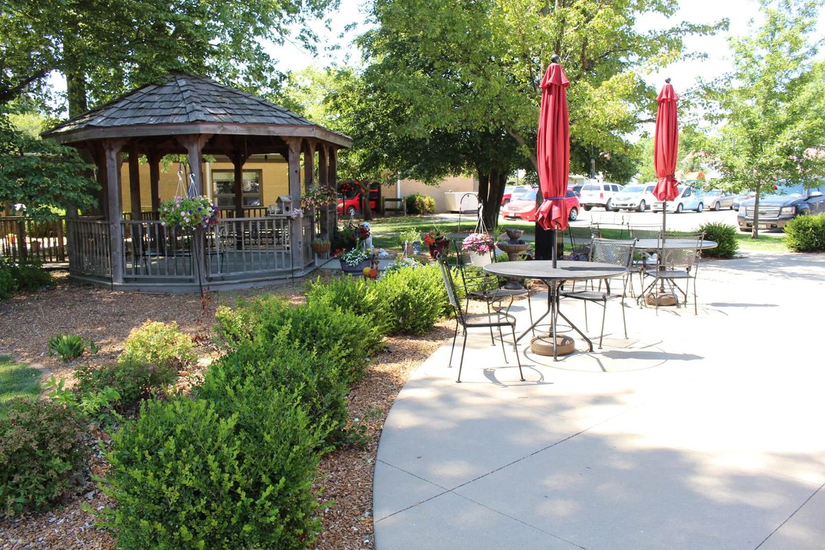 A scenic outdoor patio with a gazebo and seating areas surrounded by lush landscaping.