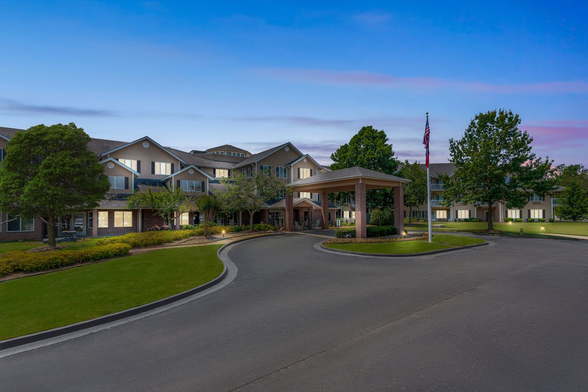 A well-maintained residential building with a circular driveway and landscaped surroundings in the evening.