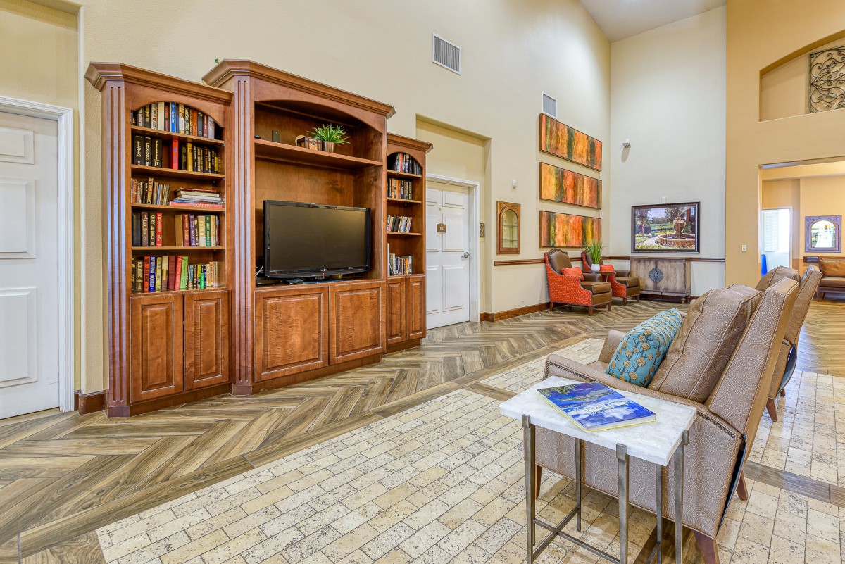 A cozy living room with a wooden bookshelf, TV, and comfortable seating area.