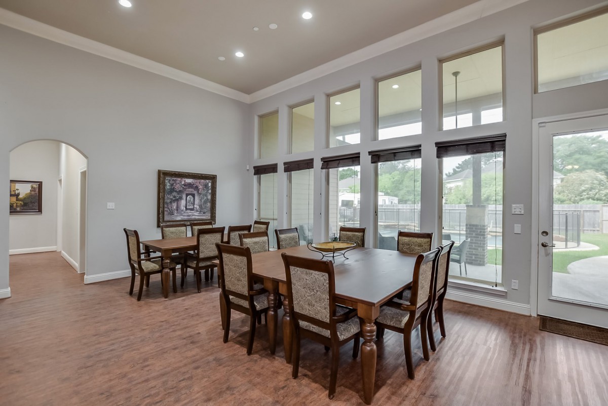 A spacious dining area with large windows, multiple tables, and wooden flooring.