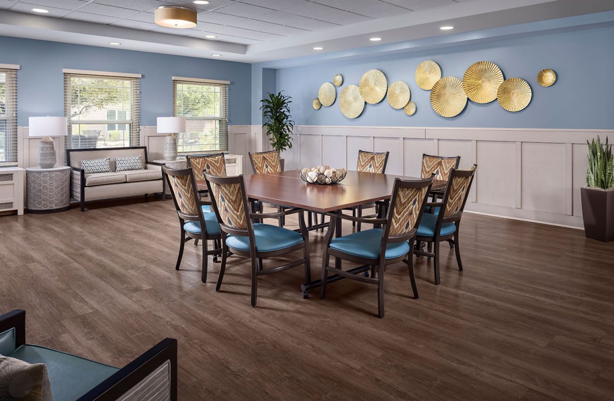 A well-decorated dining room with a large wooden table, cushioned chairs, and wall art in a bright, inviting space.