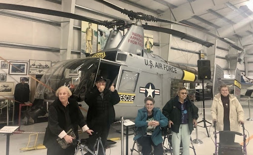 Veterans gathered in front of a U.S. Air Force helicopter at an aviation museum.