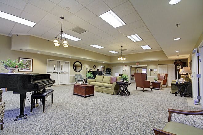 A spacious living area featuring a piano, comfortable seating, and elegant lighting.